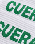 Model wearing Cuera 2-pack Cuera Padel Socks in White/Green, lifestyle action shot on the padel court