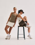 Model wearing Cuera Oncourt Slim Tank Top in Off White, lifestyle action shot on the padel court