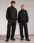 Model wearing Cuera Active Cuera Track Pants in Black, front studio view